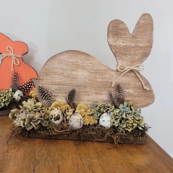Decoração de Páscoa com coelhos de madeira e flores.