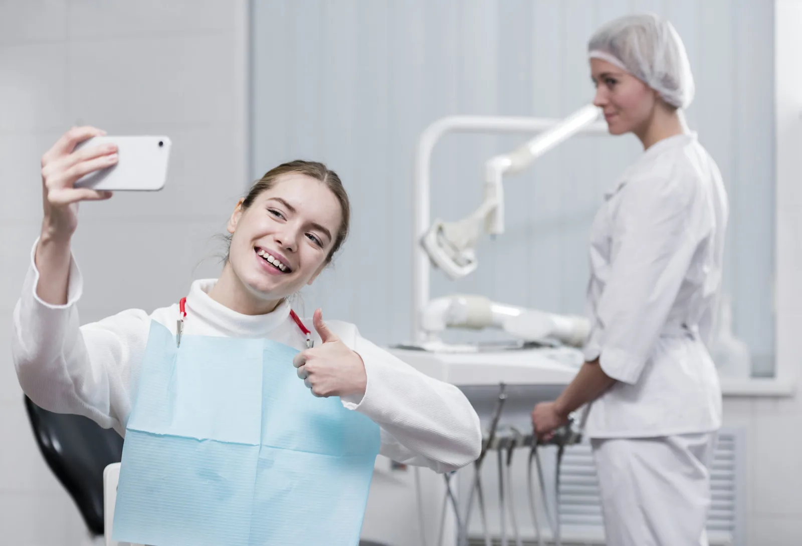 Paciente tirando uma selfie com uma profissional de odontologia.