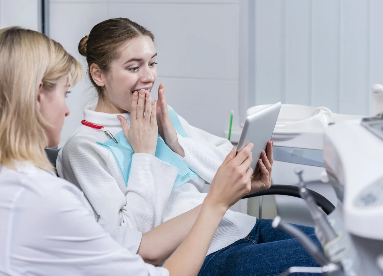 Dentista mostrando informações em um tablet a uma paciente.