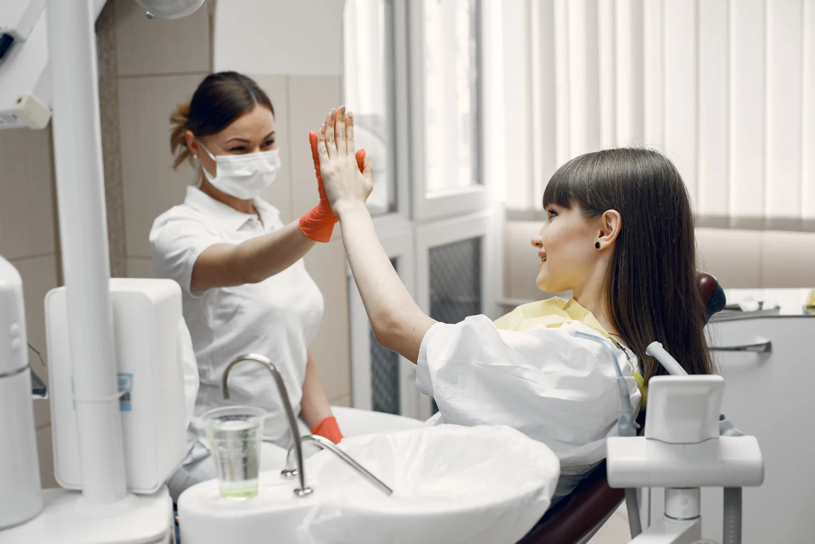 Paciente e dentista fazendo um gesto de cumprimento no consultório.