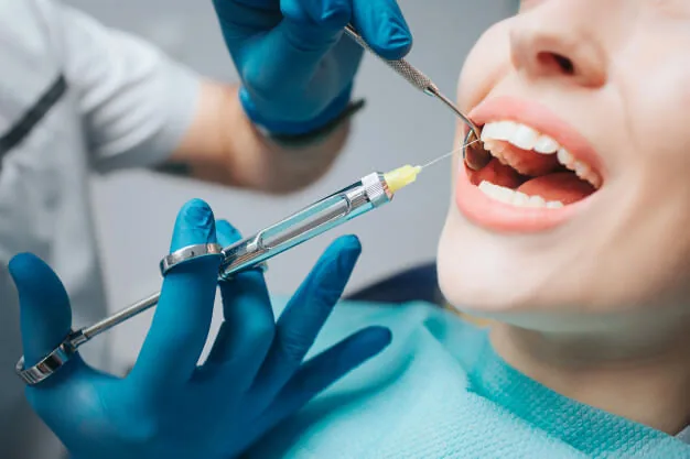 Dentista anestesiando a boca de uma paciente com seringa.