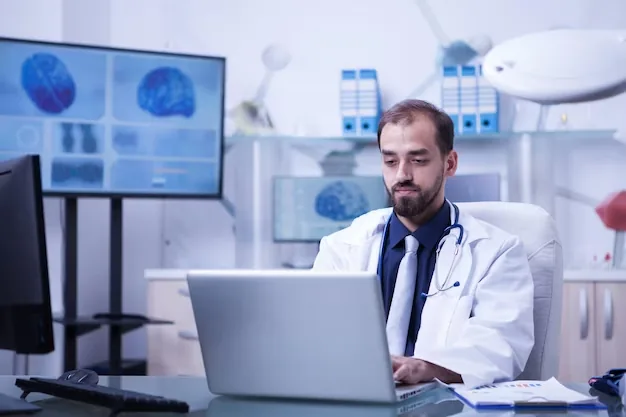 Médico trabalhando em um notebook no consultório.