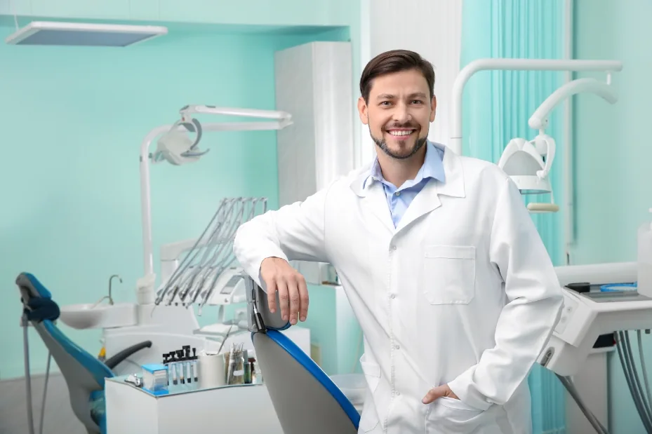 Dentista sorrindo em seu consultório odontológico.