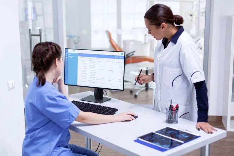 Profissionais de odontologia consultando informações em um computador.