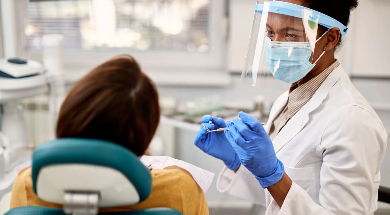 Dentista explicando um modelo de arcada dentária a uma paciente.