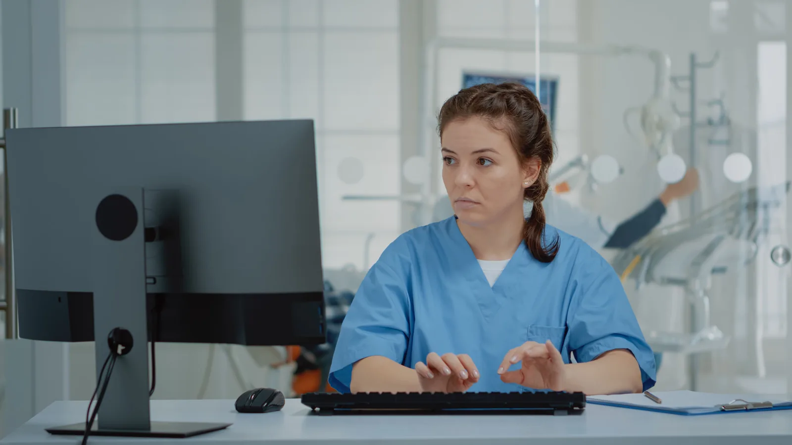 Profissional de saúde trabalhando no computador no consultório.