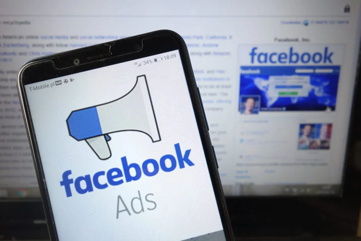 Tela do Facebook Ads em um celular diante de um computador.